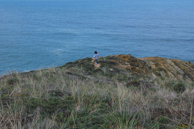 Rear view of woman standing by sea