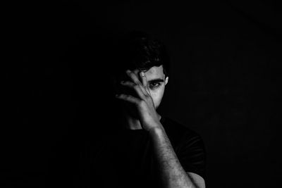 Portrait of young man against black background