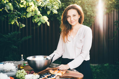 Portrait of smiling young woman preparing food at home