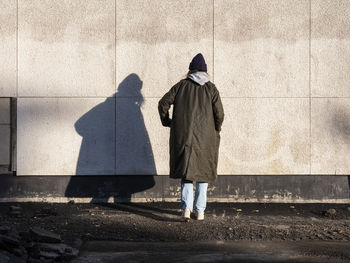 Rear view of woman standing against wall