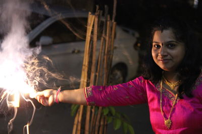 Portrait of mid adult woman playing with sparklers at night