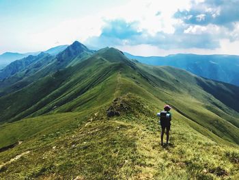 Rear view of woman hiking on mountain against sky