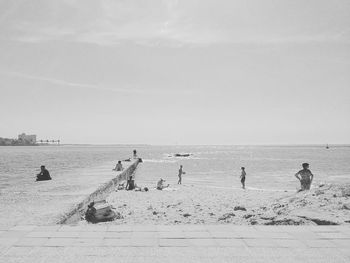 People at beach against clear sky