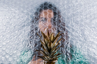 Woman by plants seen through plastic