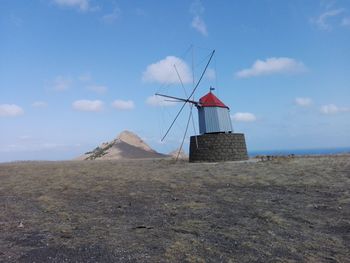 Traditional windmill on beach against sky