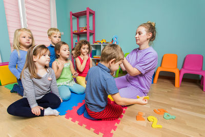 Rear view of friends sitting on wooden floor