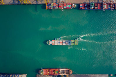 Aerial top view tugboat pushing container ship to quayside for load/unload container via crane 
