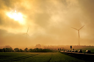 Wind turbines in the fog with morning light and cars in the foreground