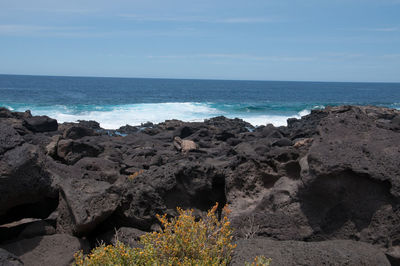 Scenic view of rocks on beach against sky