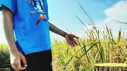 Midsection of woman standing on field against sky