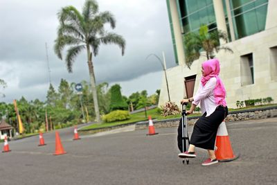 Woman sitting on traffic cone in city