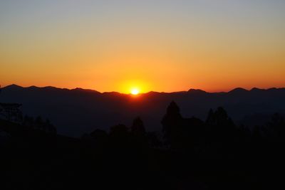 Scenic view of silhouette mountains against orange sky