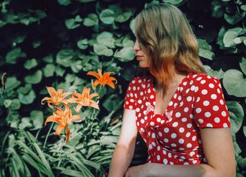 Woman with blond hair sitting by flowers against plants