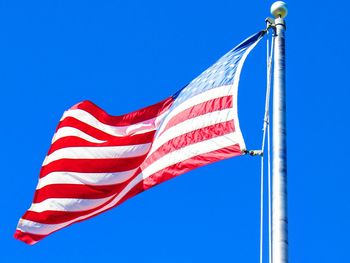 Low angle view of flags against clear blue sky