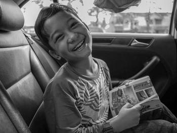 Portrait of cheerful boy sitting in car