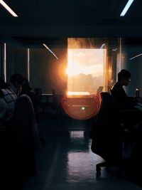 Rear view of silhouette people sitting in glass window