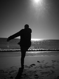 Silhouette man standing on beach against clear sky