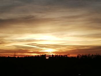 Silhouette landscape against dramatic sky during sunset