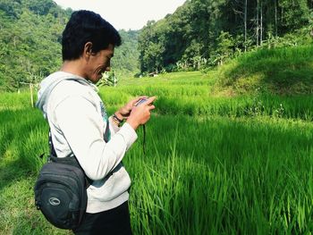 Side view of man using mobile phone on field