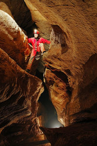Low angle view of mid adult man climbing rock in cave