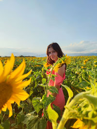 Young woman standing amidst sunflowers