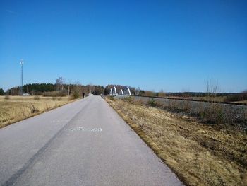 Empty road against clear blue sky