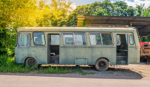 Abandoned vintage car on road against trees