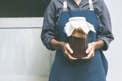 Midsection of woman standing against wall
