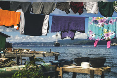 Clothes drying on clothesline by sea against sky