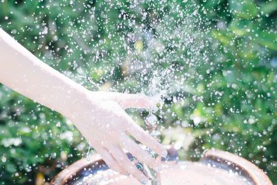 Midsection of woman splashing water in park