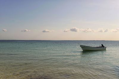 Boat in sea against sky during sunset