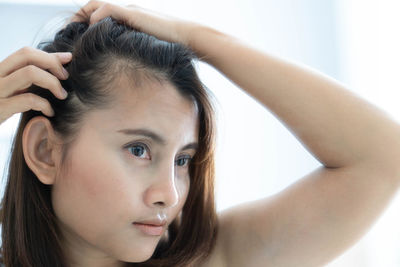 Close-up portrait of beautiful young woman with hand in hair