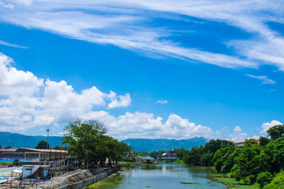 River amidst trees and buildings against blue sky