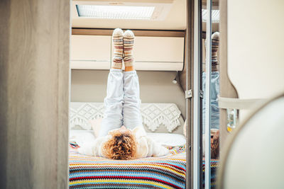 Rear view of woman lying on bed in motor home