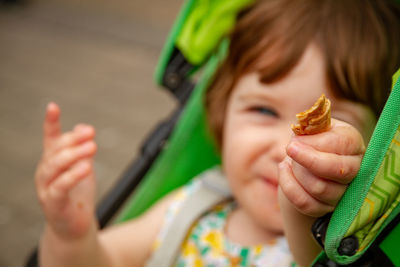 Close-up of baby girl holding food on carriage