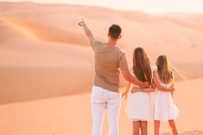 Rear view of woman standing on sand dune