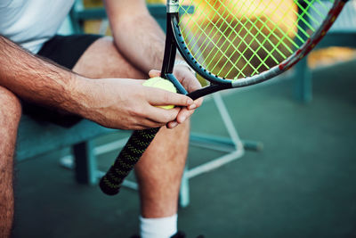 Midsection of man holding racket