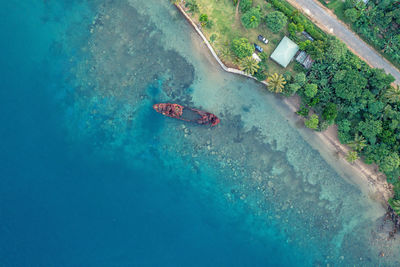 Top view of rusty wrecked boat in turquoise water near tropical shore. drone photo. sanma, vanuatu