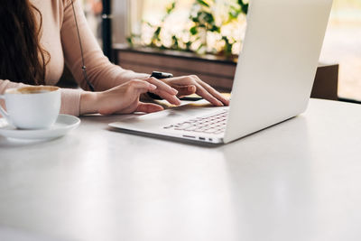 Midsection of woman using laptop on table