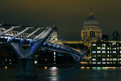 Illuminated bridge over river against sky in city at night