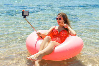 Young woman relaxing on inflatable ring in sea during summer