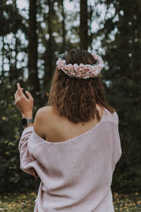 Rear view of woman standing by tree against plants