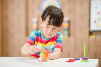 Boy holding toy while sitting on table