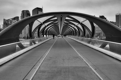 Footbridge in city against sky