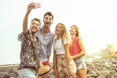 Full length portrait of smiling young woman using mobile phone