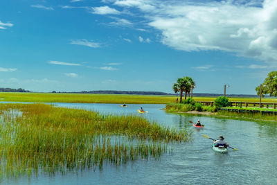 People kayaking in lake against sky