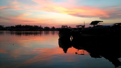 Silhouette man on boat at lake against sky during sunset