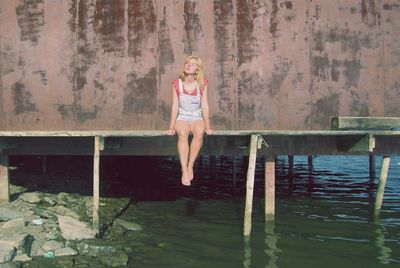 Young woman sitting on pier at seashore