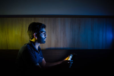 Side view of young man drinking at home