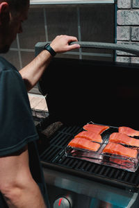 Midsection of man preparing food on barbecue grill